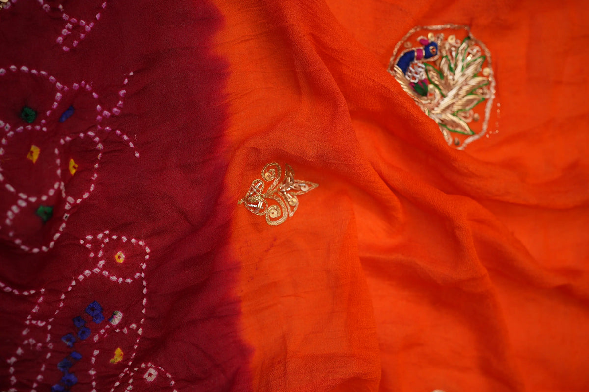 Close-up detail showing orange-maroon Bandhej tie-dye contrast and embroidered peacock butta
