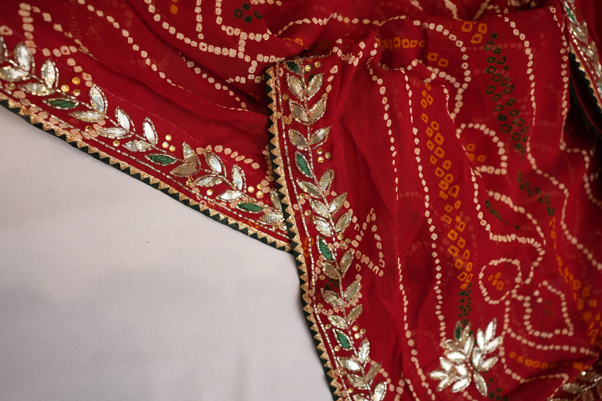 Close-up of Gota Patti vine bel embroidery with green Resham highlights on Red Bandhej Chunri border