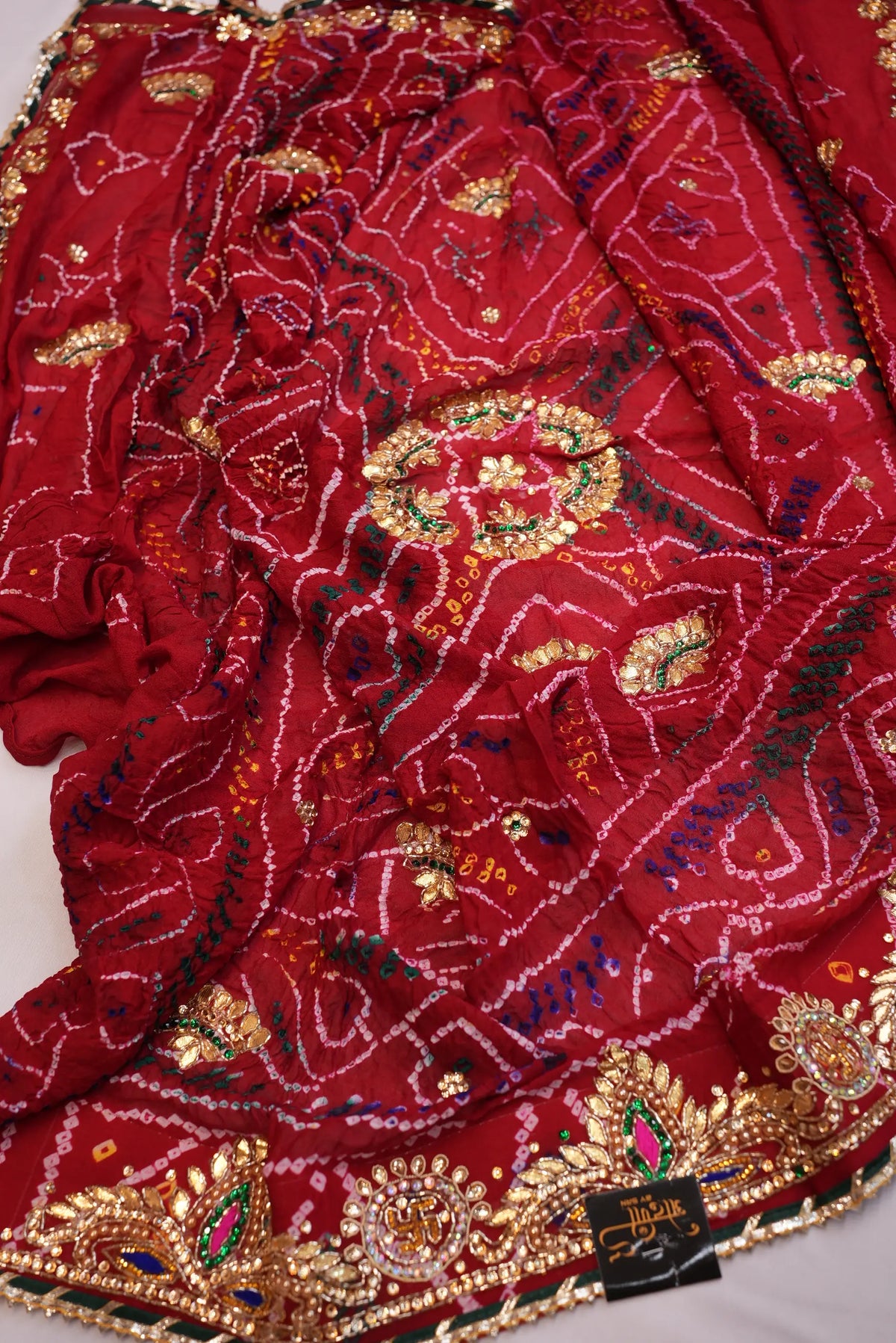 Folded view of Maroon Ojariya Bandhani Dupatta showing heavy Cut Dana border with Odhani by SRN brand tag