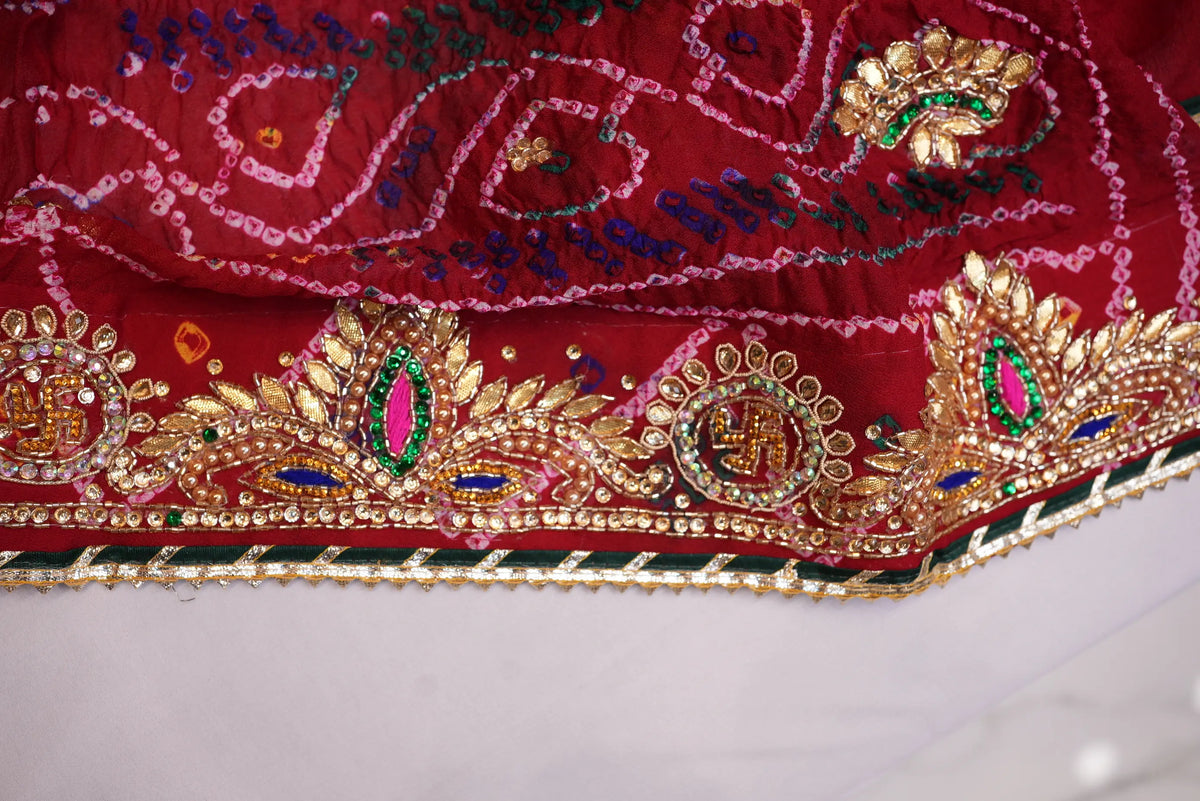 Extreme close-up of heavy Cut Dana embroidered border featuring Swastik motifs and green stone highlights