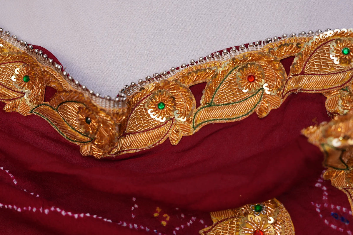 Close-up view of golden leaf lace border featuring sequin work and green stone details