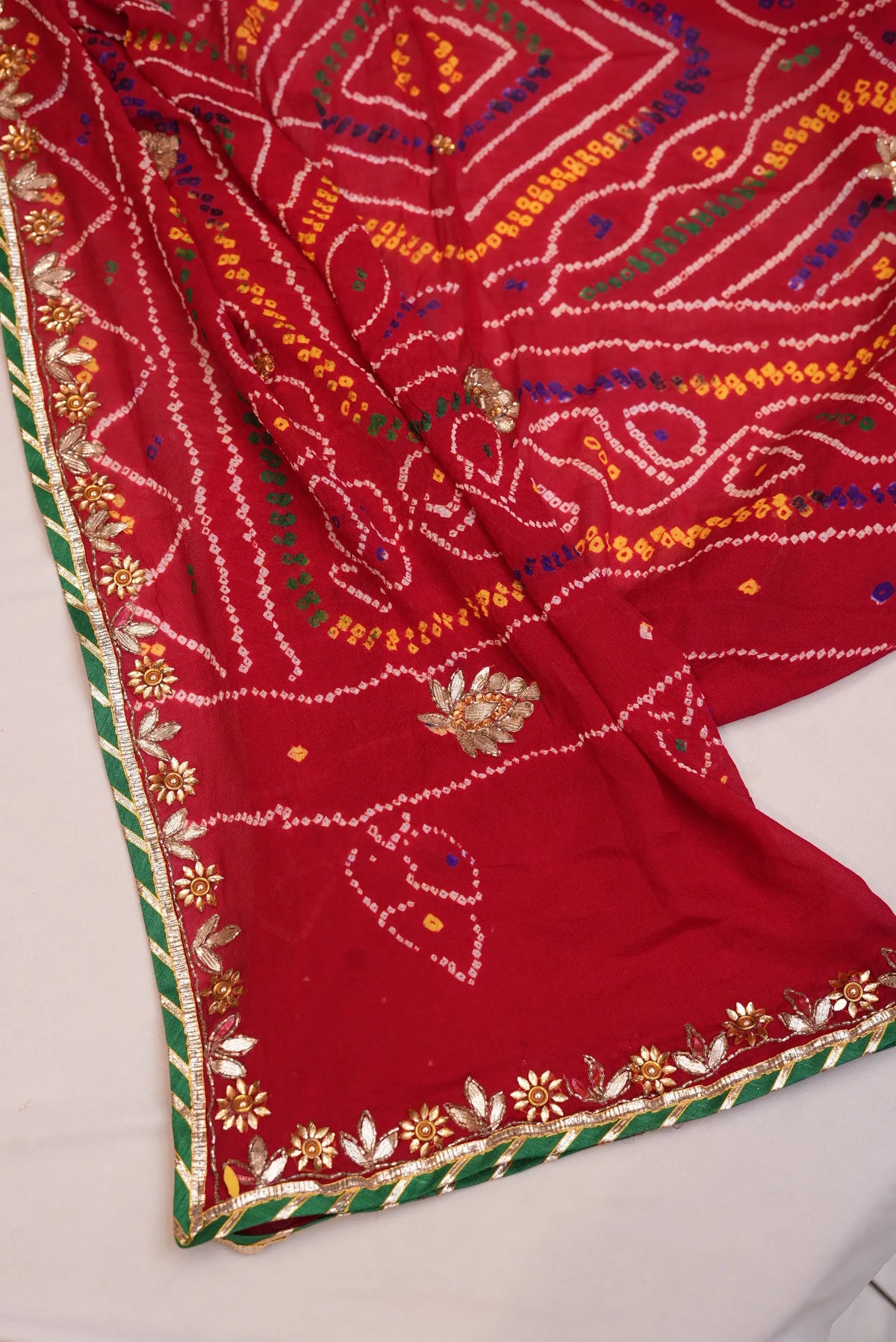 Corner view of bright red Georgette Ojariya Bandhani Chunri with Gotta Patti border and green striped piping