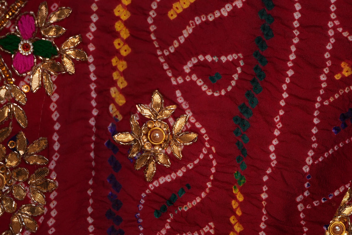 Close-up view of gold Zardozi flower motif and multi-color Ojariya Bandhej pattern on maroon Georgette fabric