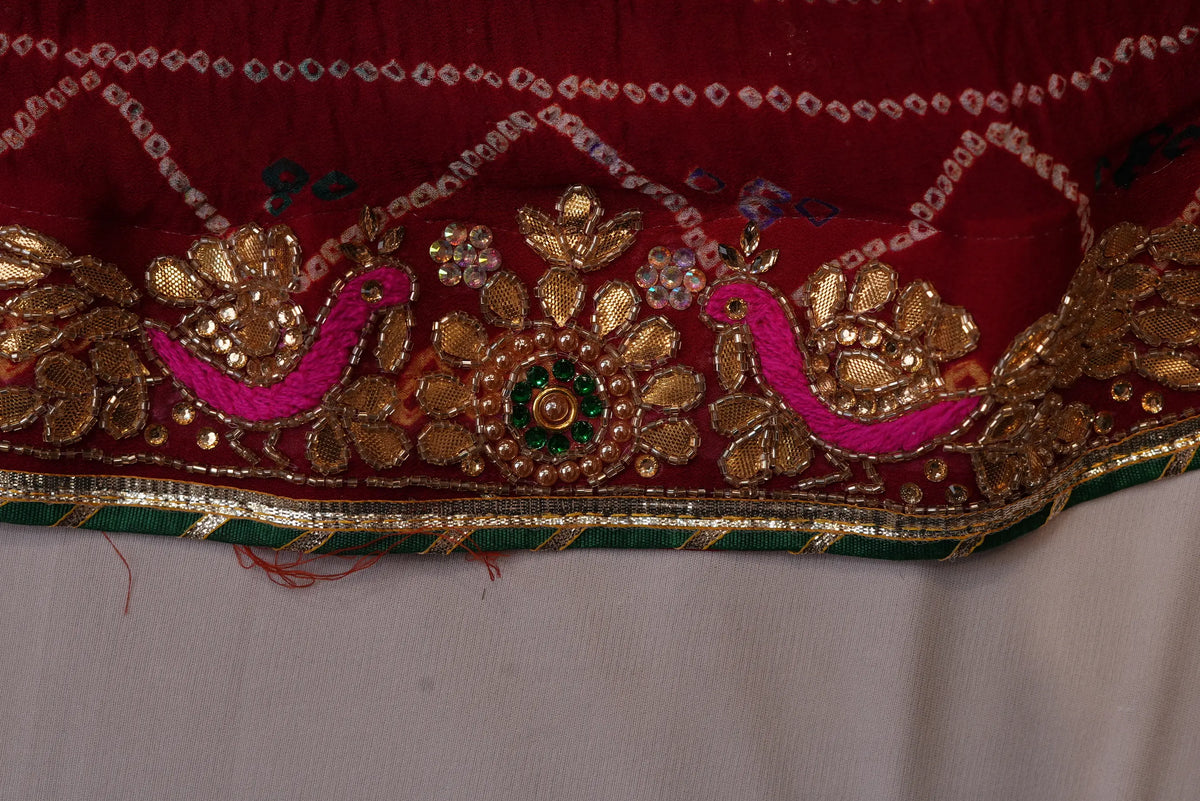 Detailed view of pink embroidered bird motif on heavy gold Zardozi border