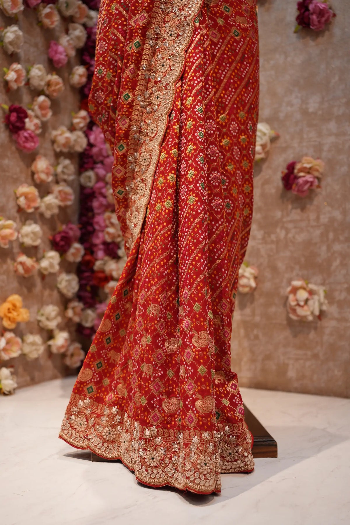 Lower skirt pleats view of red bandhani silk saree showing the heavy hand-embroidered border