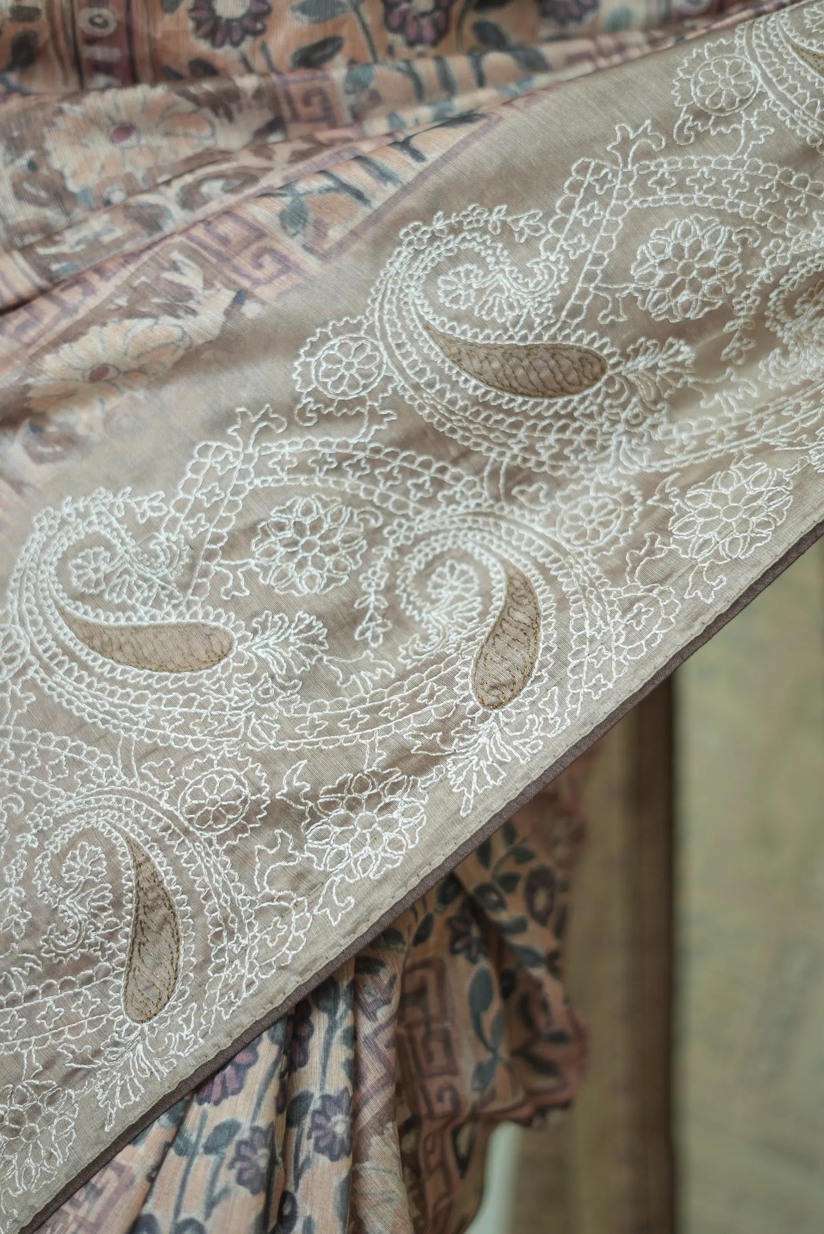 Macro detail of white thread needlework on paisley border of beige cotton mix saree
