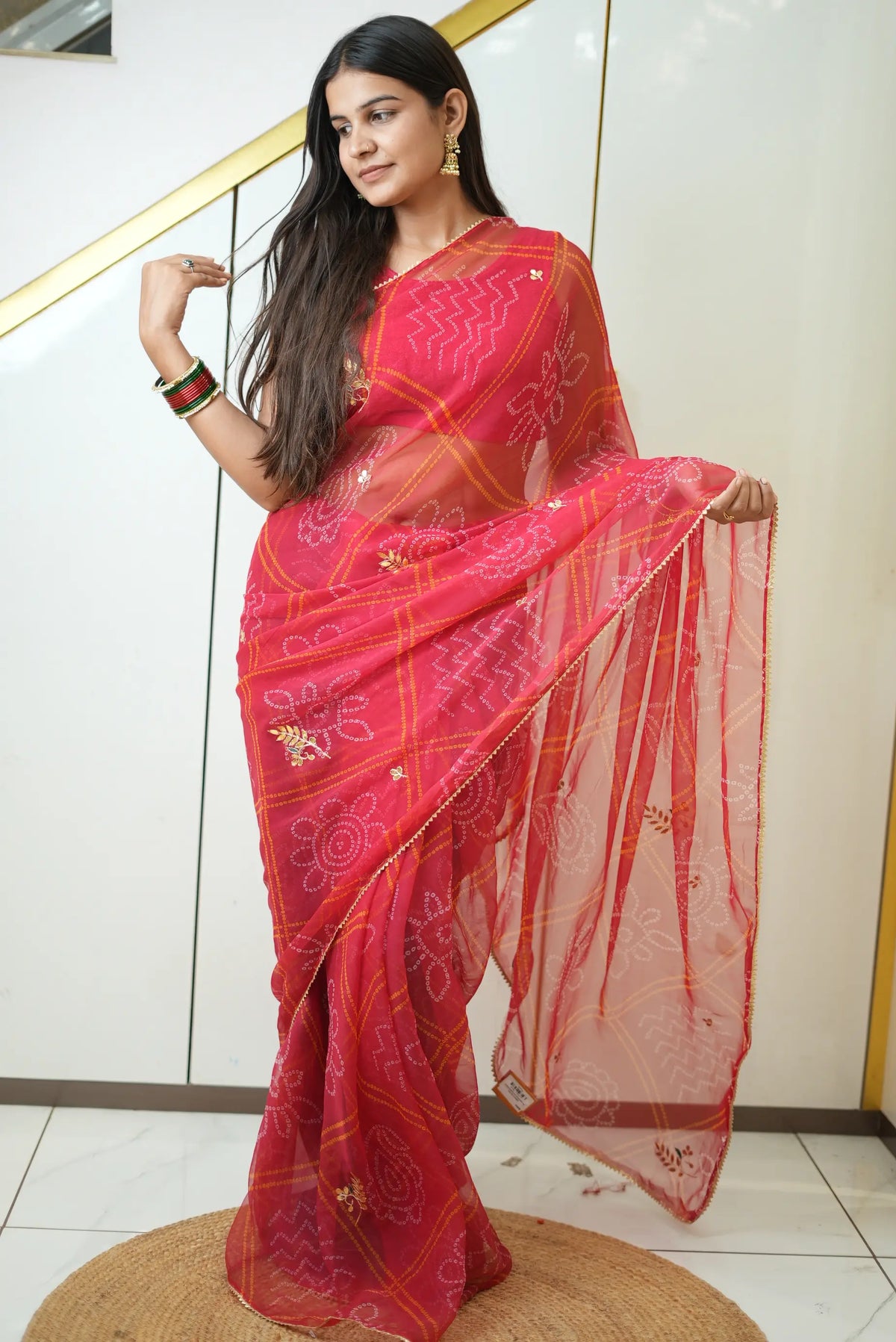 Model wearing vibrant pink printed bandhej saree with golden lace and gota patti embroidery