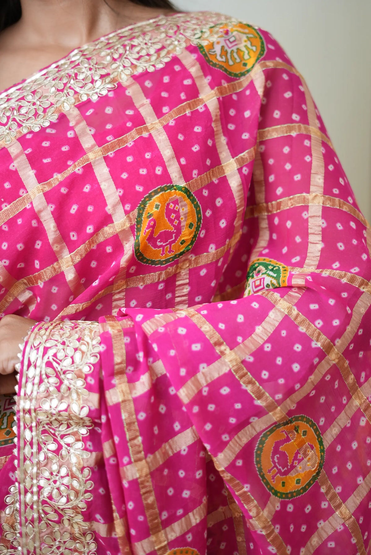 Close-up of rani pink pure gajji silk bandhani saree with heavy gota patti border and peacock motif