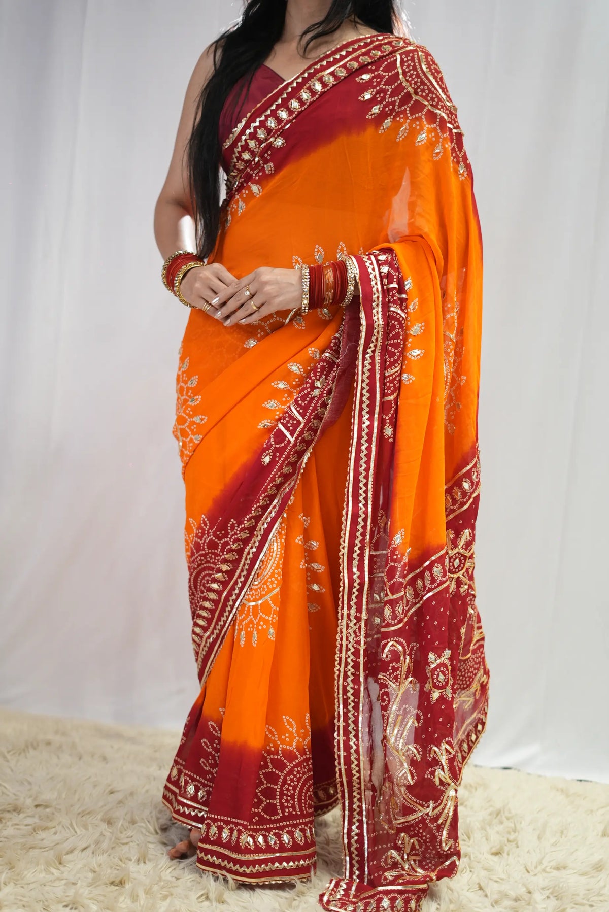 Full length pose of model wearing yellow and red dual-tone georgette bandhani saree