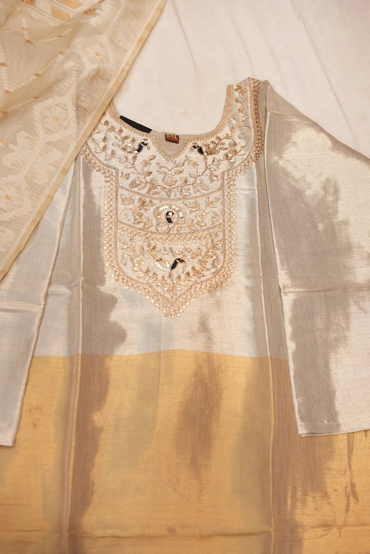 Close up view of metallic off white and golden tissue kurti yoke with zari and zardosi peacock embroidery
