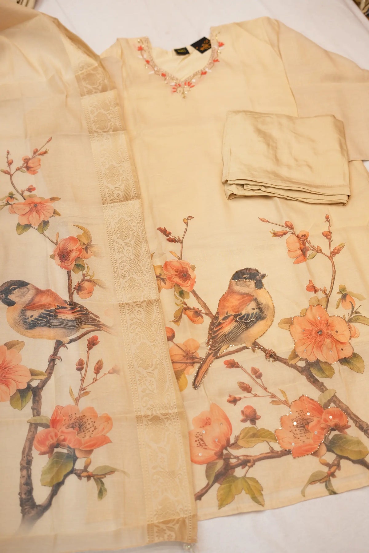 Detailed view of bird and flower digital print on light golden shimmer tissue fabric