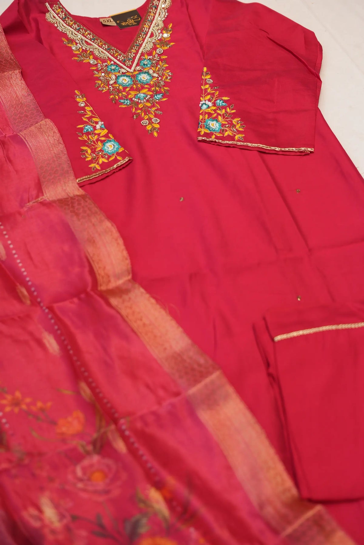 Top angle flat lay display of rani pink embroidered silk suit set with printed organza dupatta