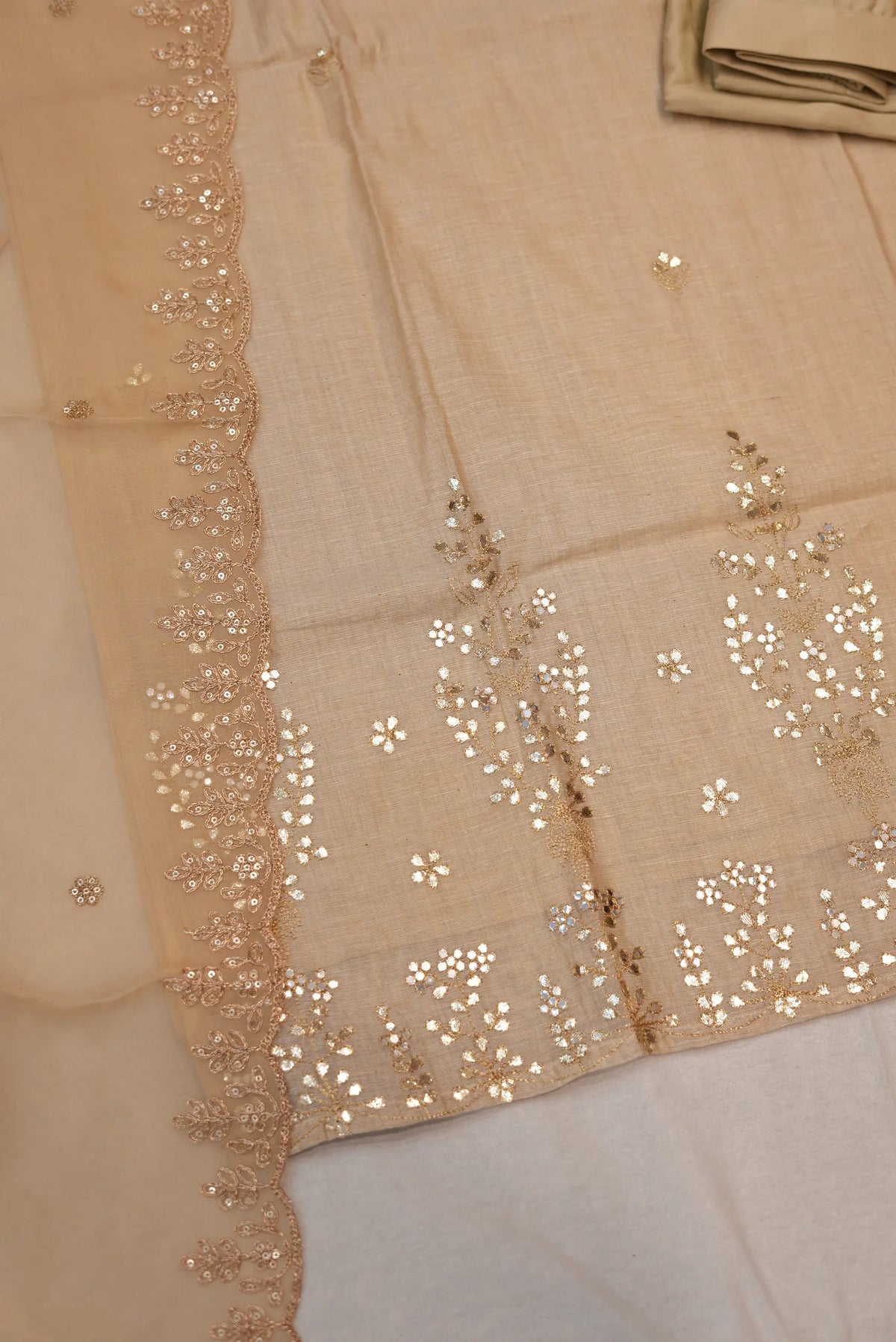 Flat lay of beige cotton khadi suit set featuring gotta patti embroidered daman and scalloped dupatta border
