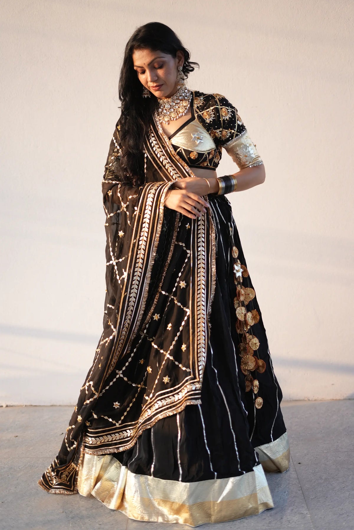 Full length pose of model wearing 12 meter flared rajasthani lappa lehenga set with custom blouse and gota jaal dupatta