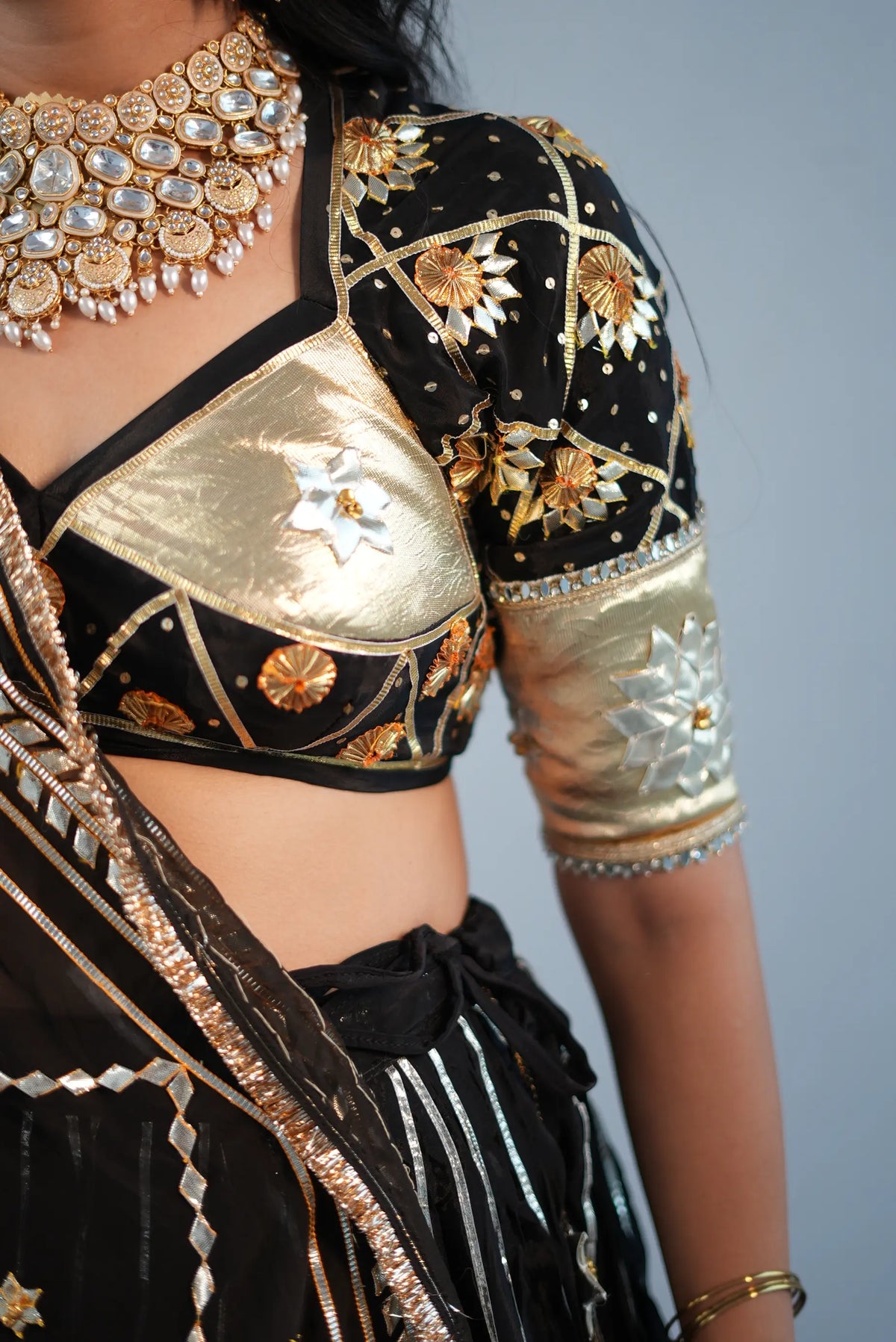 Side profile view of custom fitted black blouse with gold metallic patches and gota work