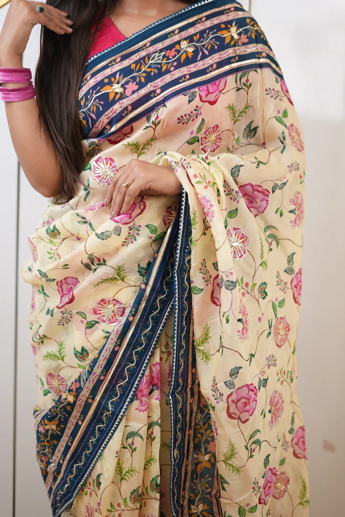 Lower drape view showing pleats and contrast peacock blue patterned hemline on cream tissue saree