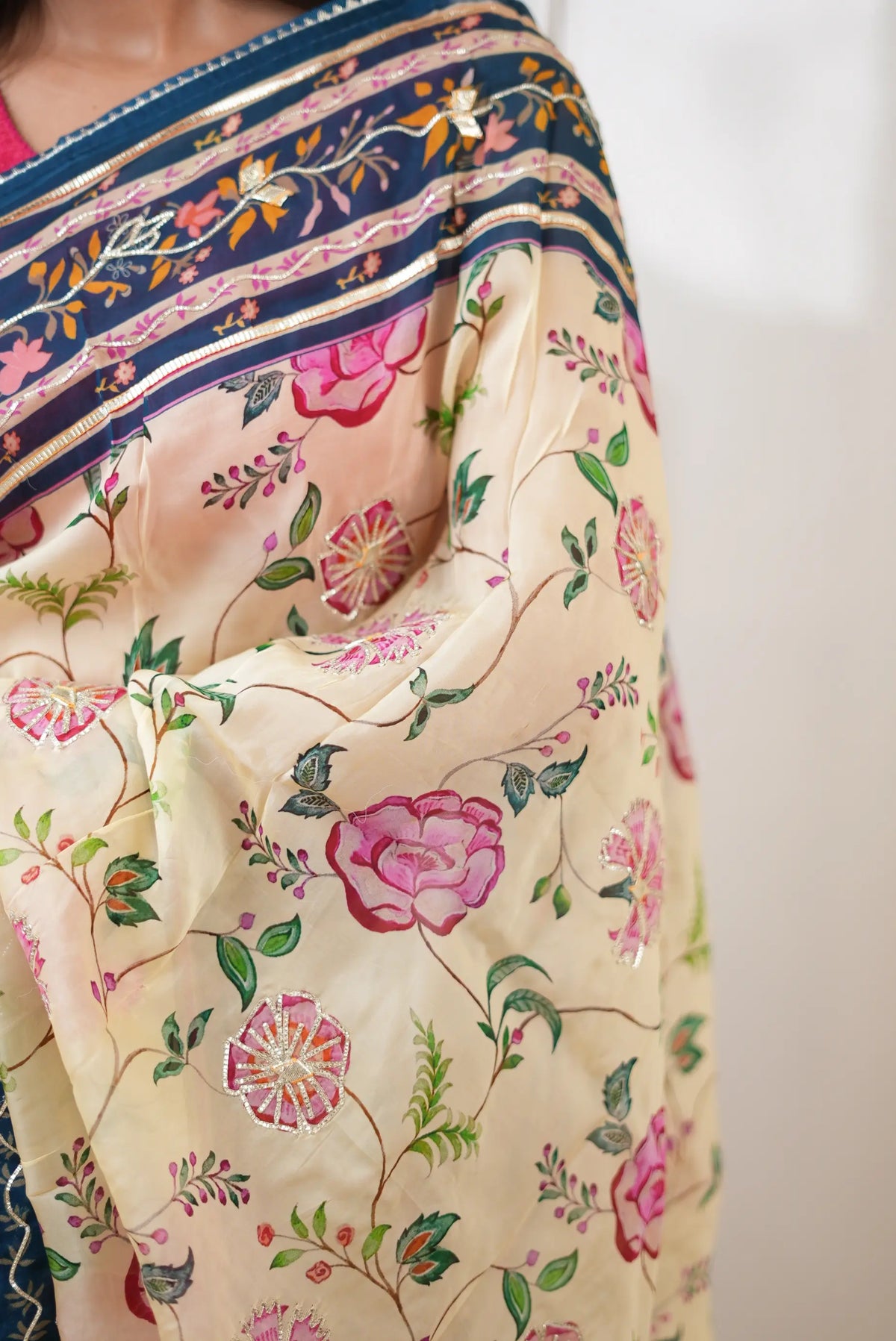 Detailed view of cream tissue fabric with pink floral prints and handworked gota patti circular motifs