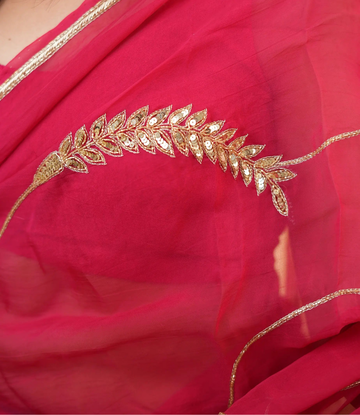 Close up shot of leaf motif handwork with gold sequins, cutdana, and zardozi zari work on rani pink pure organza saree