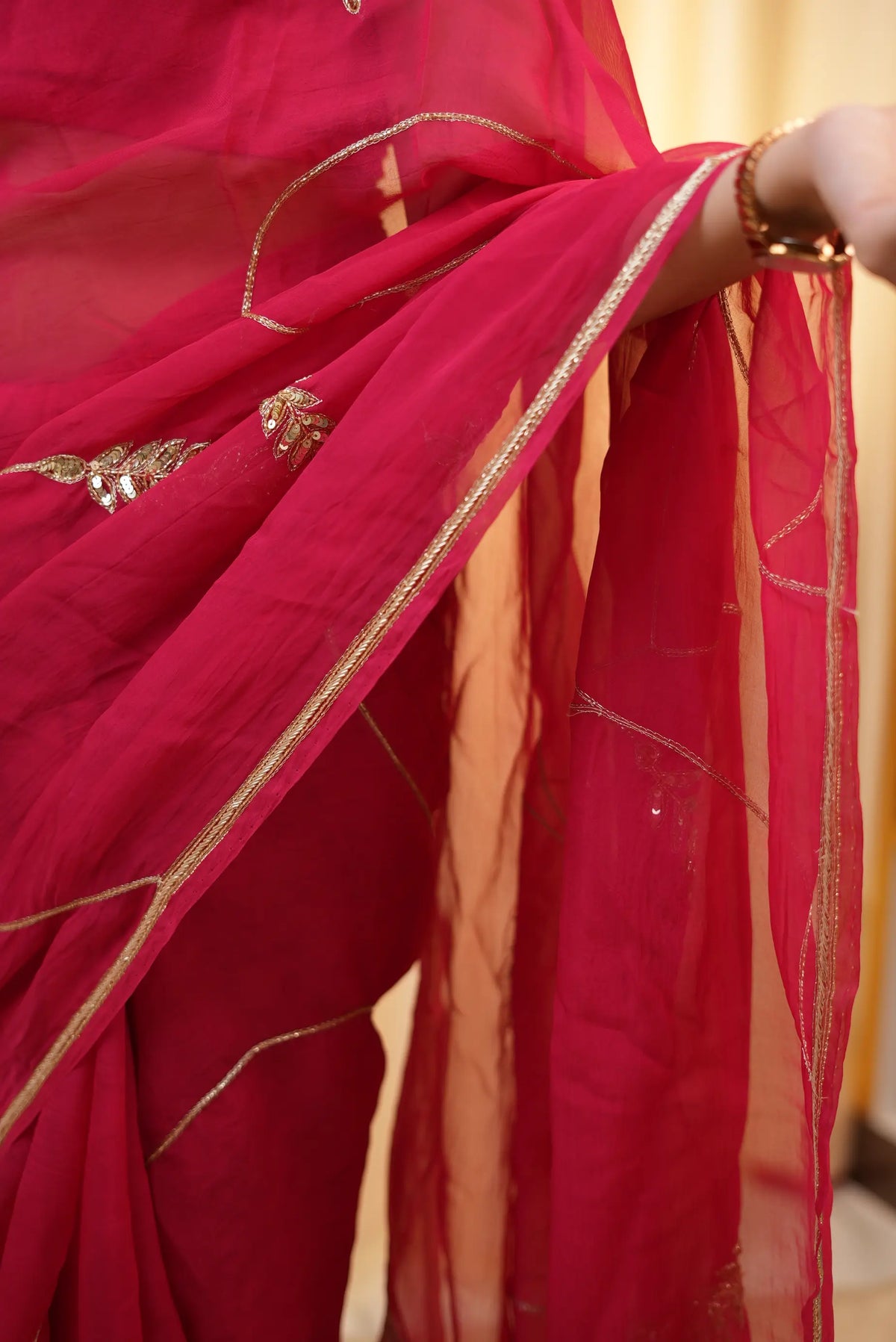 Model demonstrating the graceful drape and thin metallic border of rani pink organza saree
