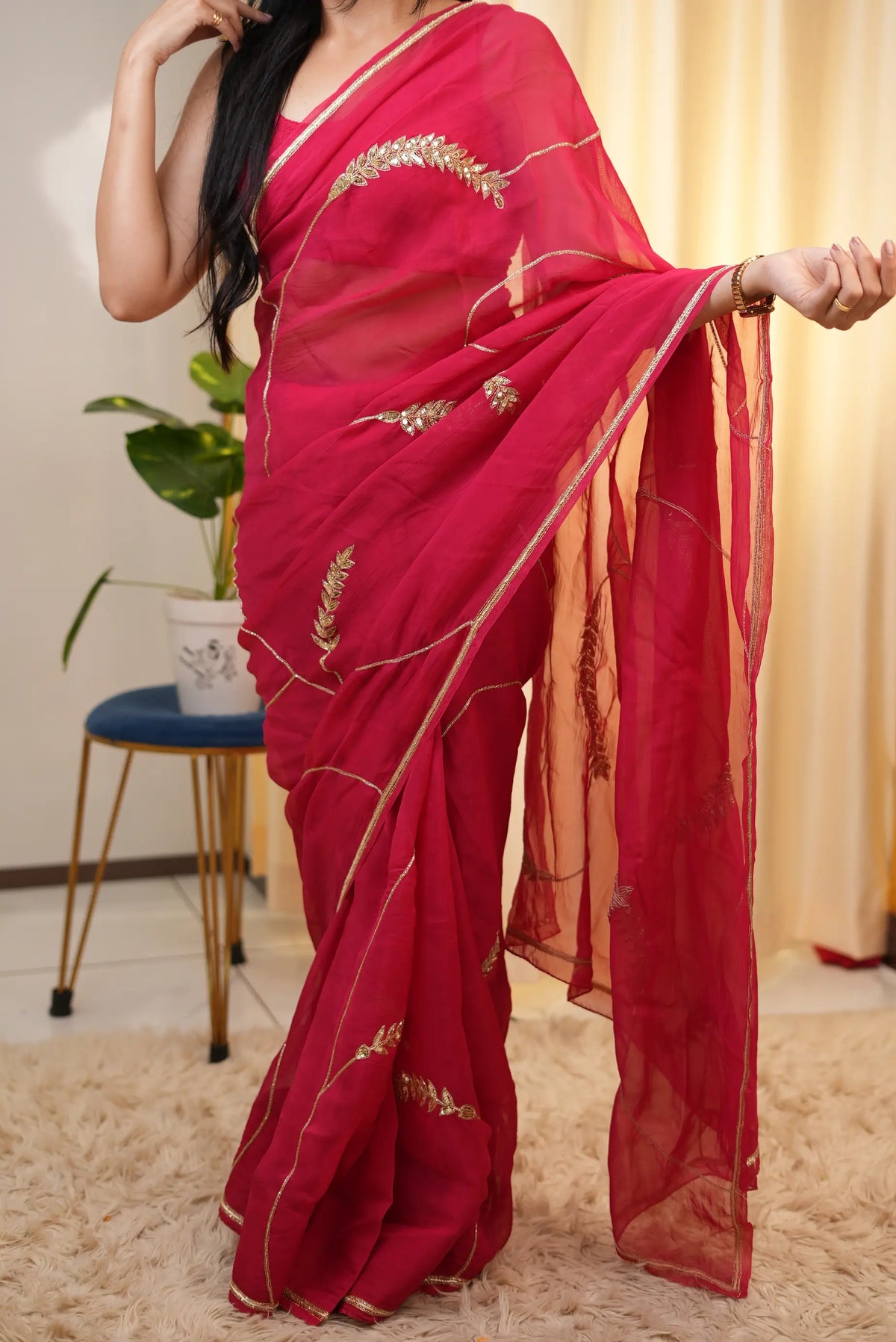 Front view display of rani pink organza saree showing pallu drapes and all-over scattered leaf motifs