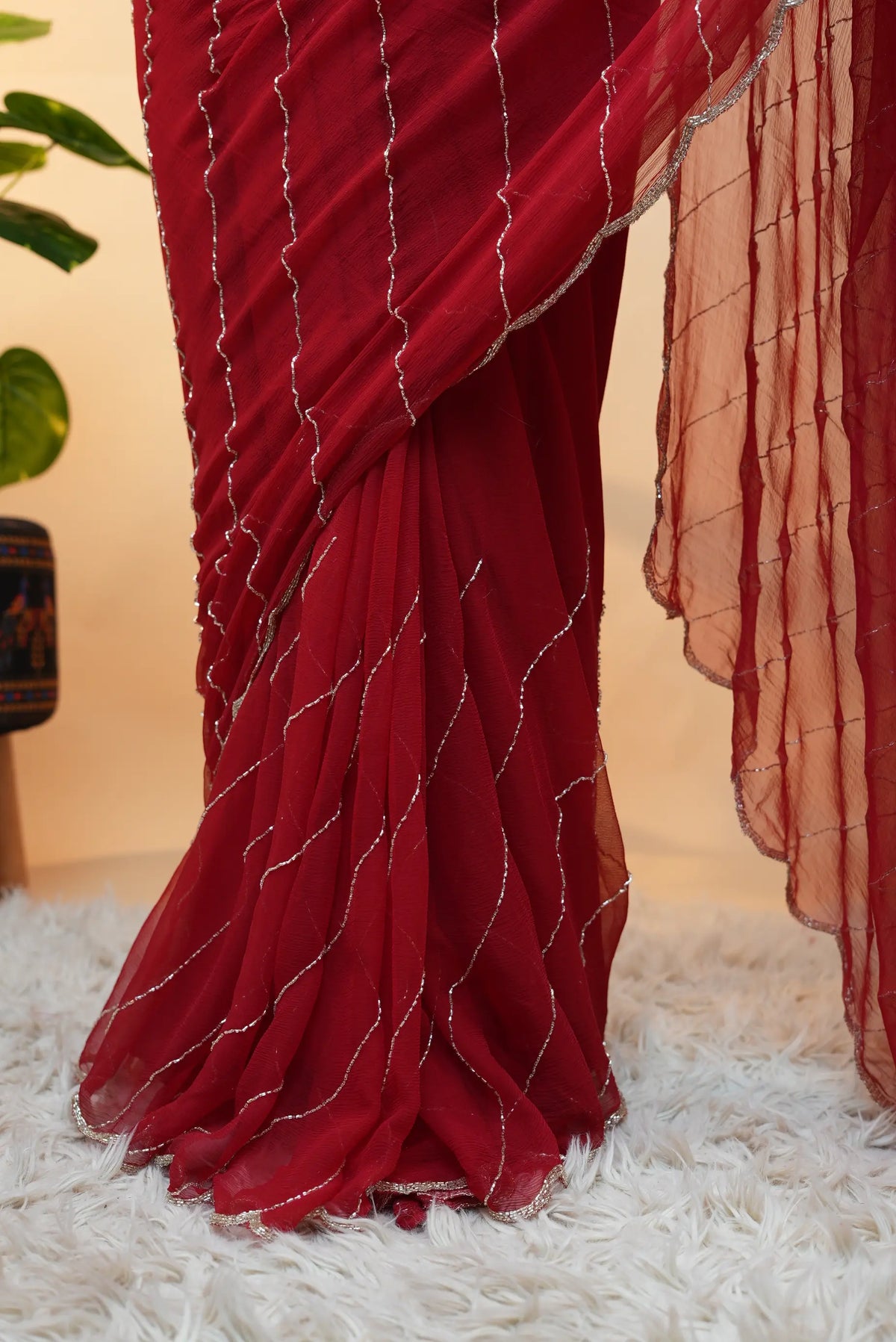 Lower pleats detail of red pure chiffon saree displaying vertical cutdana lines and flowy hem