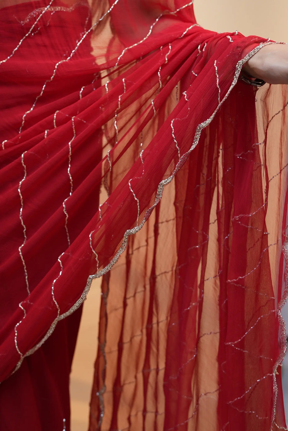 Detailed view of sheer red pure chiffon pallu drapes with scalloped cutdana border