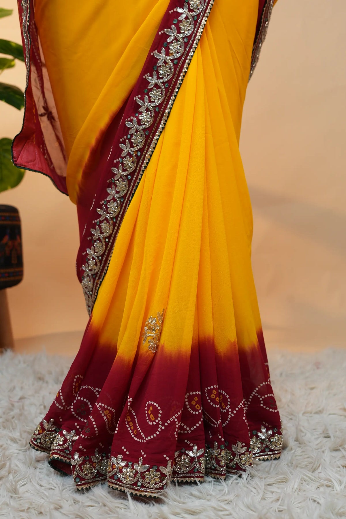 Lower pleats detail of yellow Viscose Georgette saree with deep red bandhani border and handwork trim