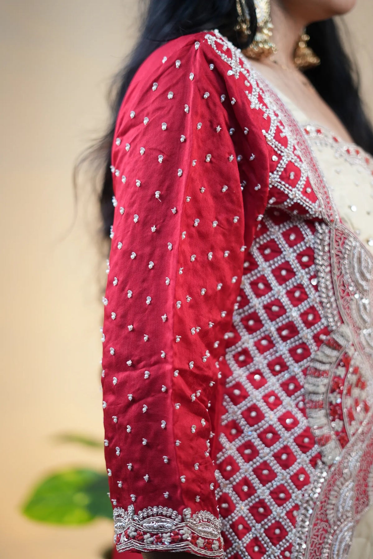 Sleeve detail of red H.O. silk jacket sprinkled with white pearls and embellished cuff border