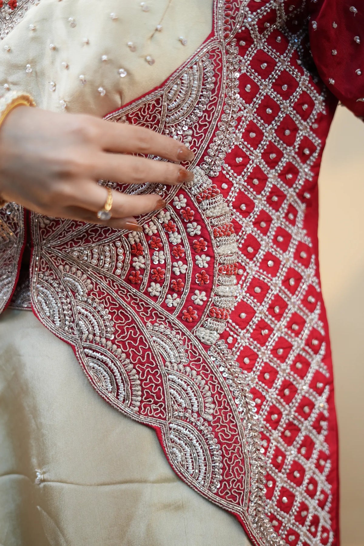 Macro close-up shot of crimson red jacket butterfly front cutwork showing white pearl, cutdana, sequin, and zardozi handwork