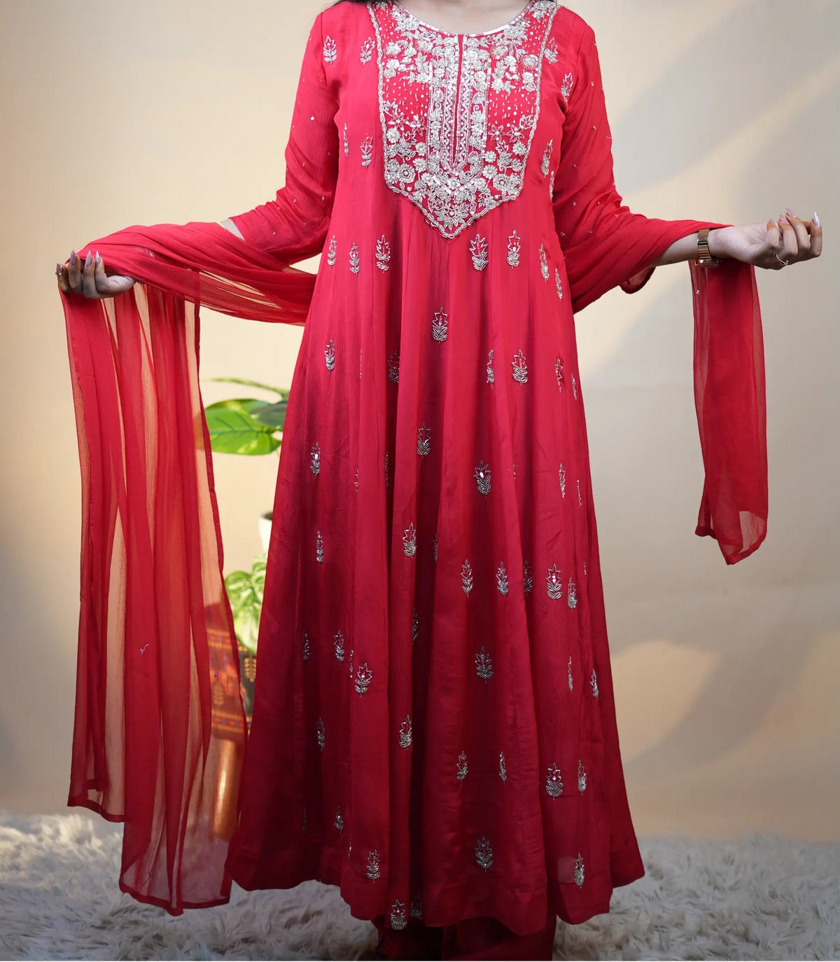 Model holding red chiffon dupatta spread wide alongside floor length pure silk anarkali kurta