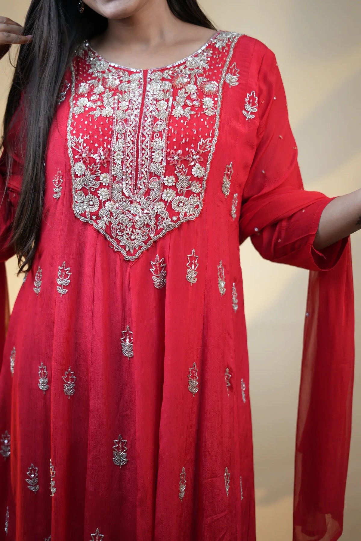 Mid shot view of model wearing red silk anarkali suit with heavy embroidered neck design