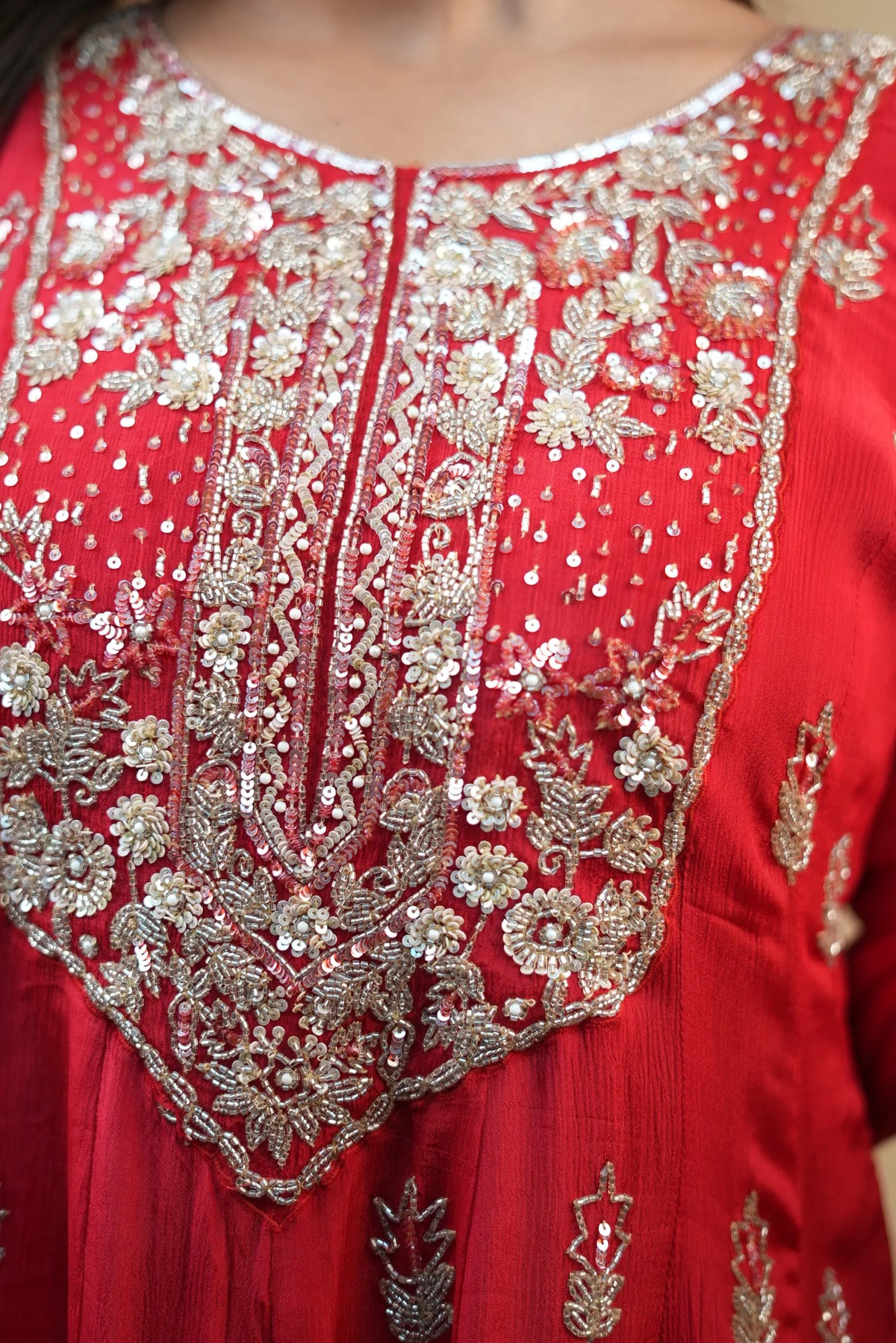 Macro close up shot of red pure silk anarkali yoke showing cutdana beads, white moti pearls, and sequin flower work