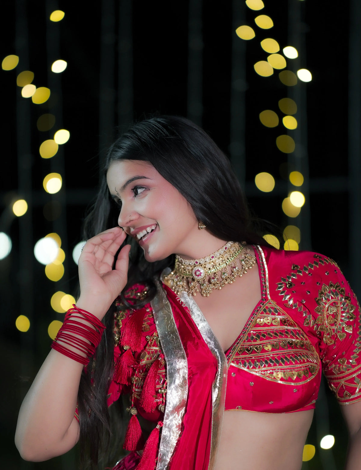 Model smiling in red pure crepe Aangi blouse showcasing gold heart sequin work and detailed neck embellishments