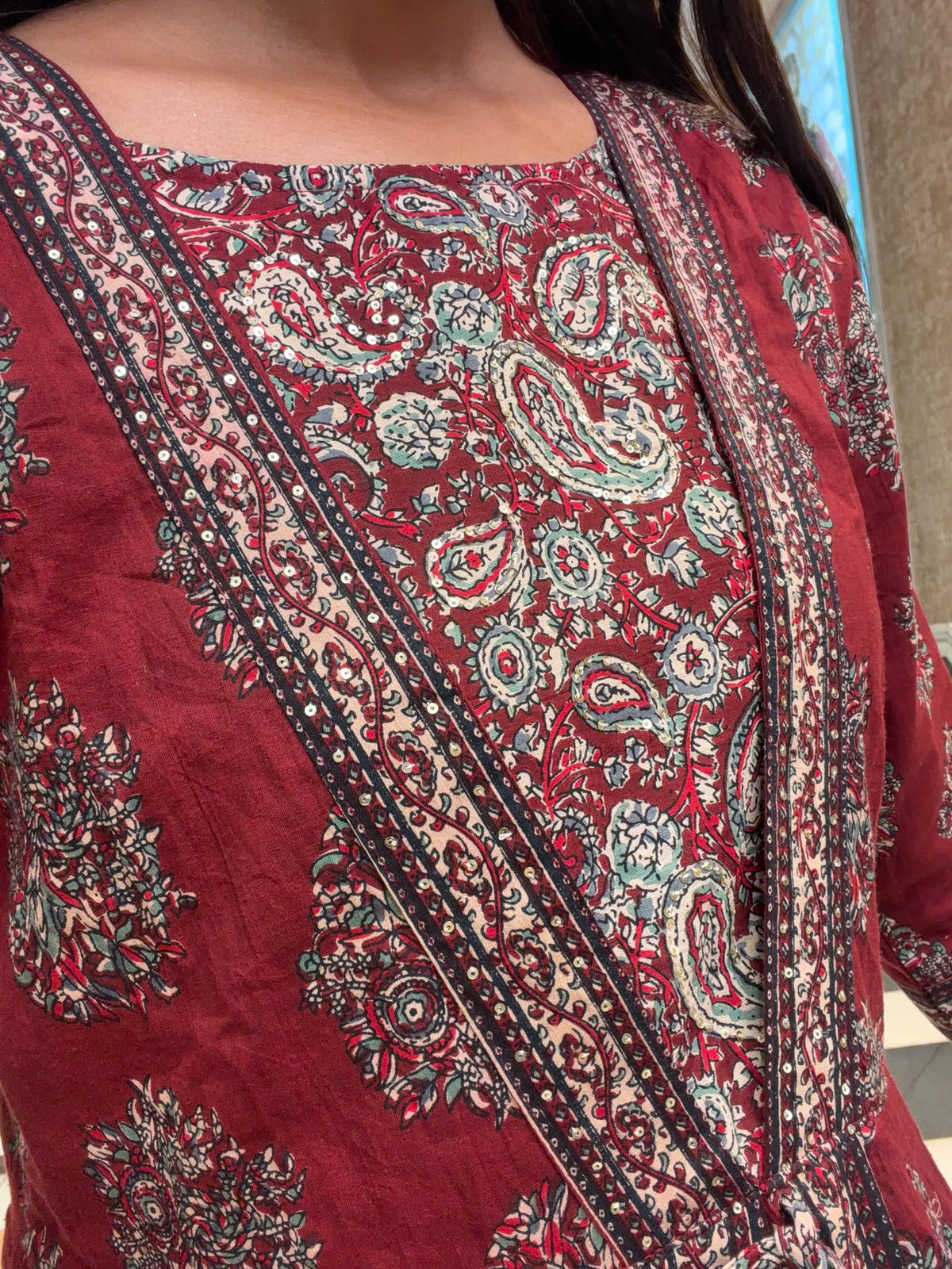 Close-up detail of paisley Kalamkari block print and subtle sequin embroidery border on kurti yoke