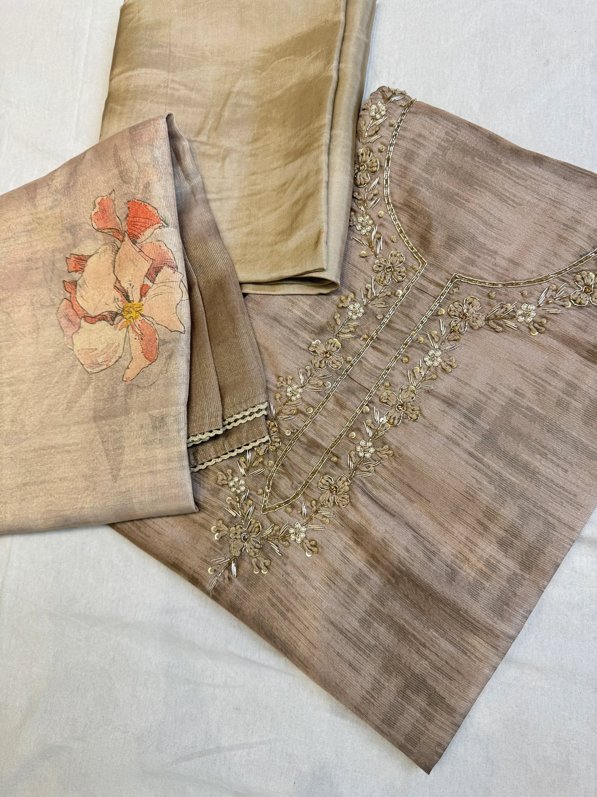 Flat lay shot of mouse grey tissue silk unstitched suit material with hand embroidered neckline and floral printed dupatta