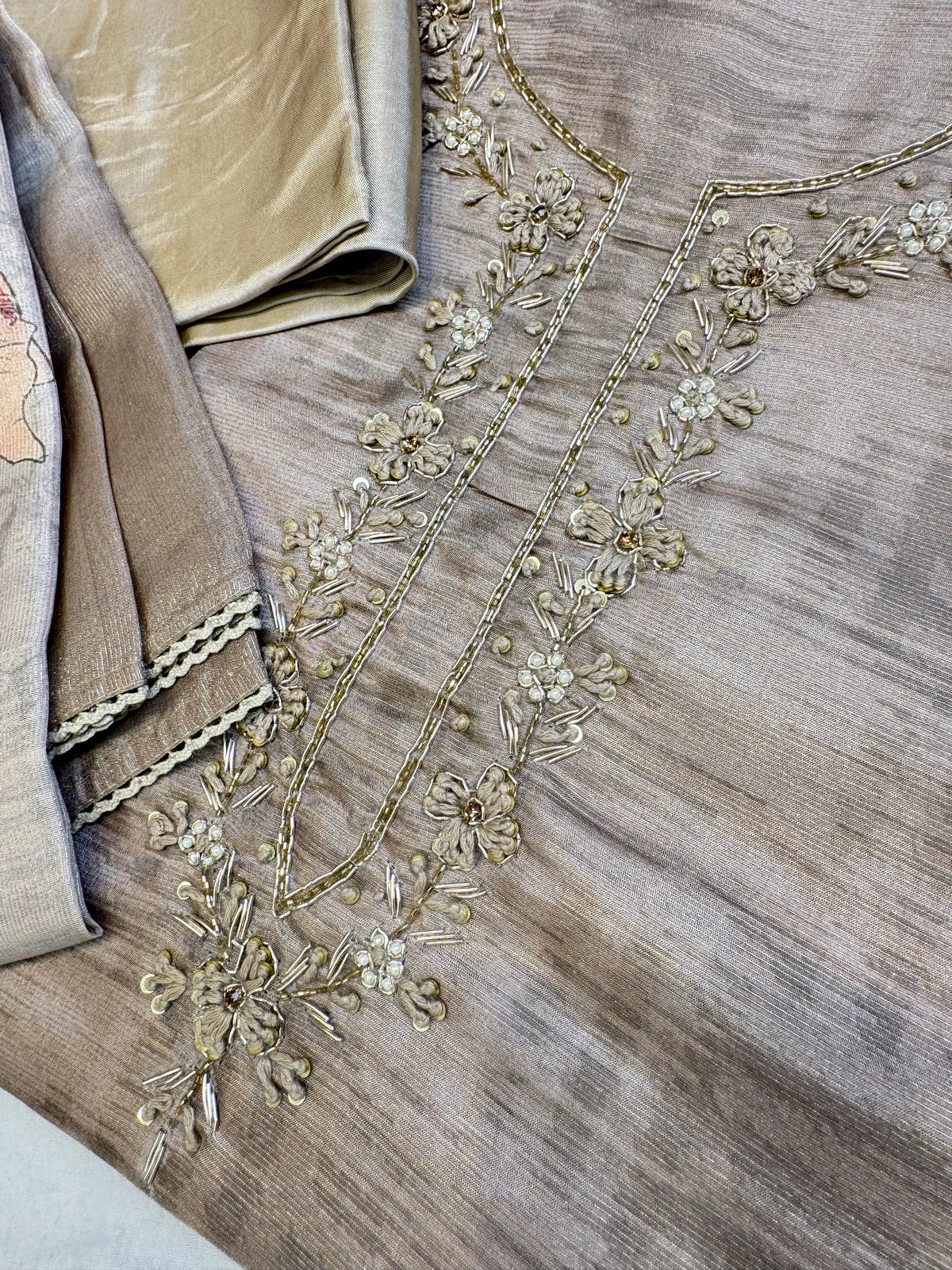 Close up view of tissue suit neckline featuring zardozi embroidery, cutdana beads, white pearls, and mulmul thread floral motifs