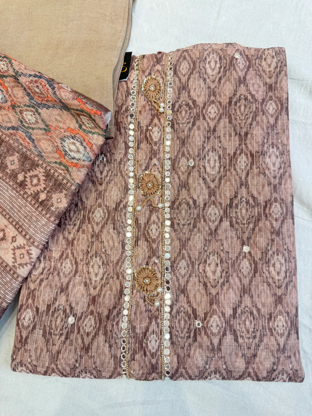 Close up view of tissue suit front panel with mirror work placket, pearl moti details, and thread flower motifs