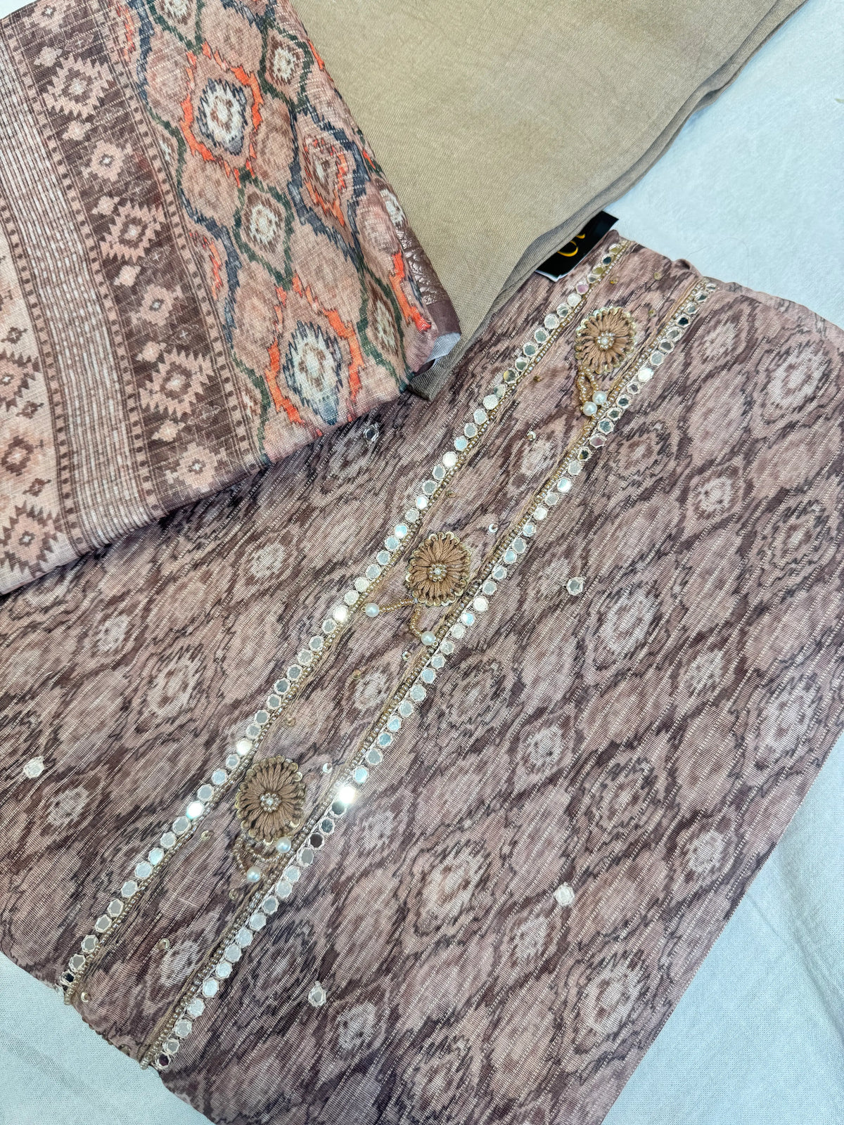 Top angle view of brown tissue silk kurti fabric showing mirror border neck design and matching solid bottom
