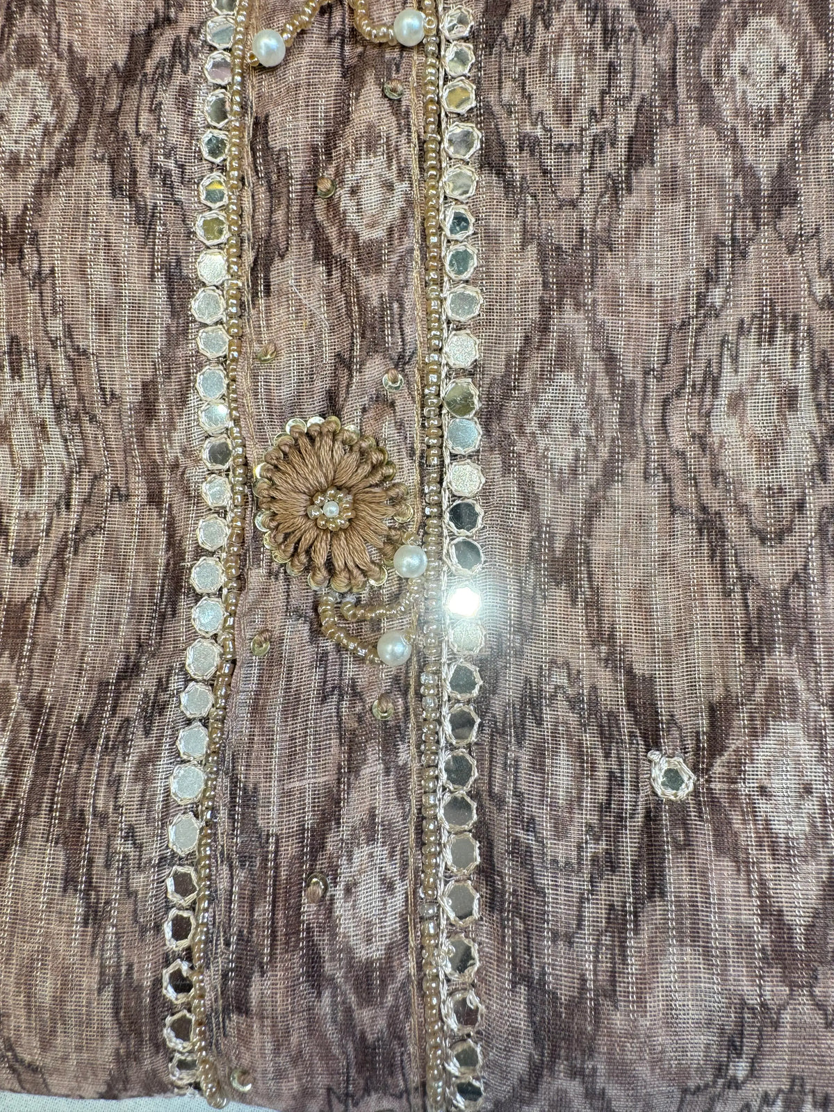 Extreme close up shot of handworked thread motif with white pearl and glittering mirror border