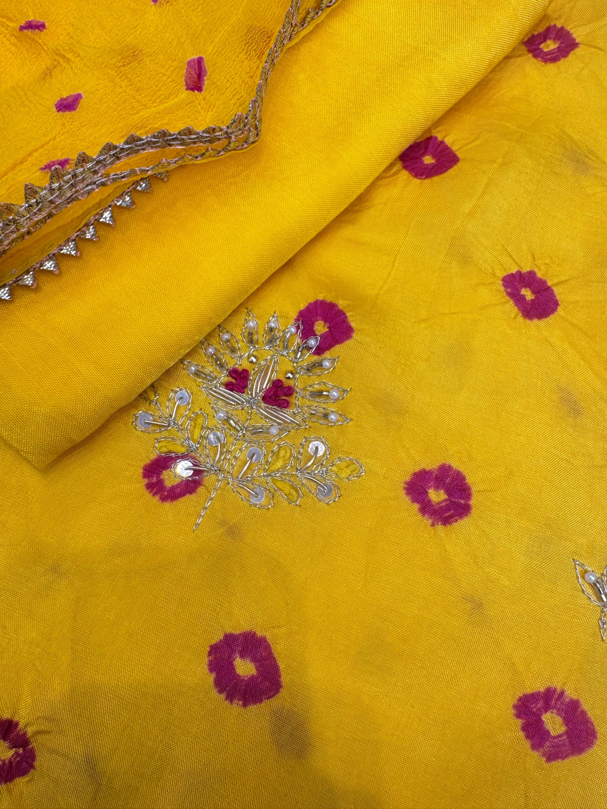 Close up view of hand embroidered buti on yellow silk bandhej suit with white pearls and sequin work