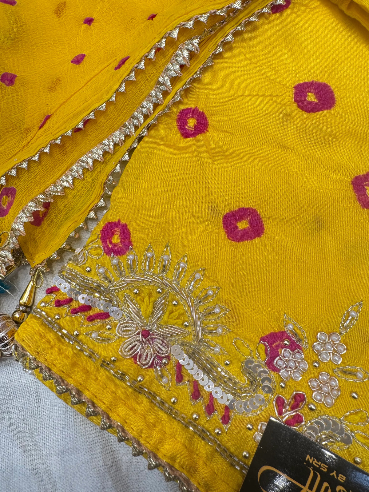 Detailed macro shot of suit daman border displaying zardozi embroidery, cutdana beads, and real white moti work