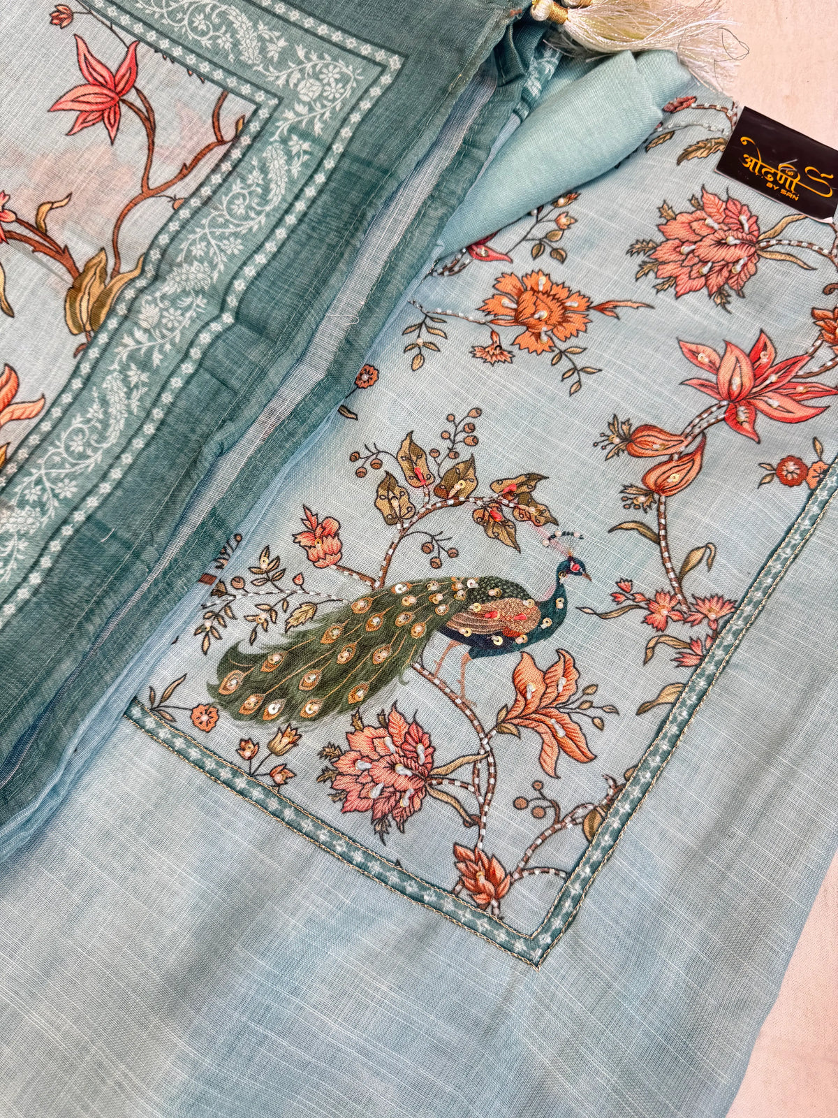 Flat lay shot of sky blue unstitched cotton doria suit material set with peacock motif and floral dupatta