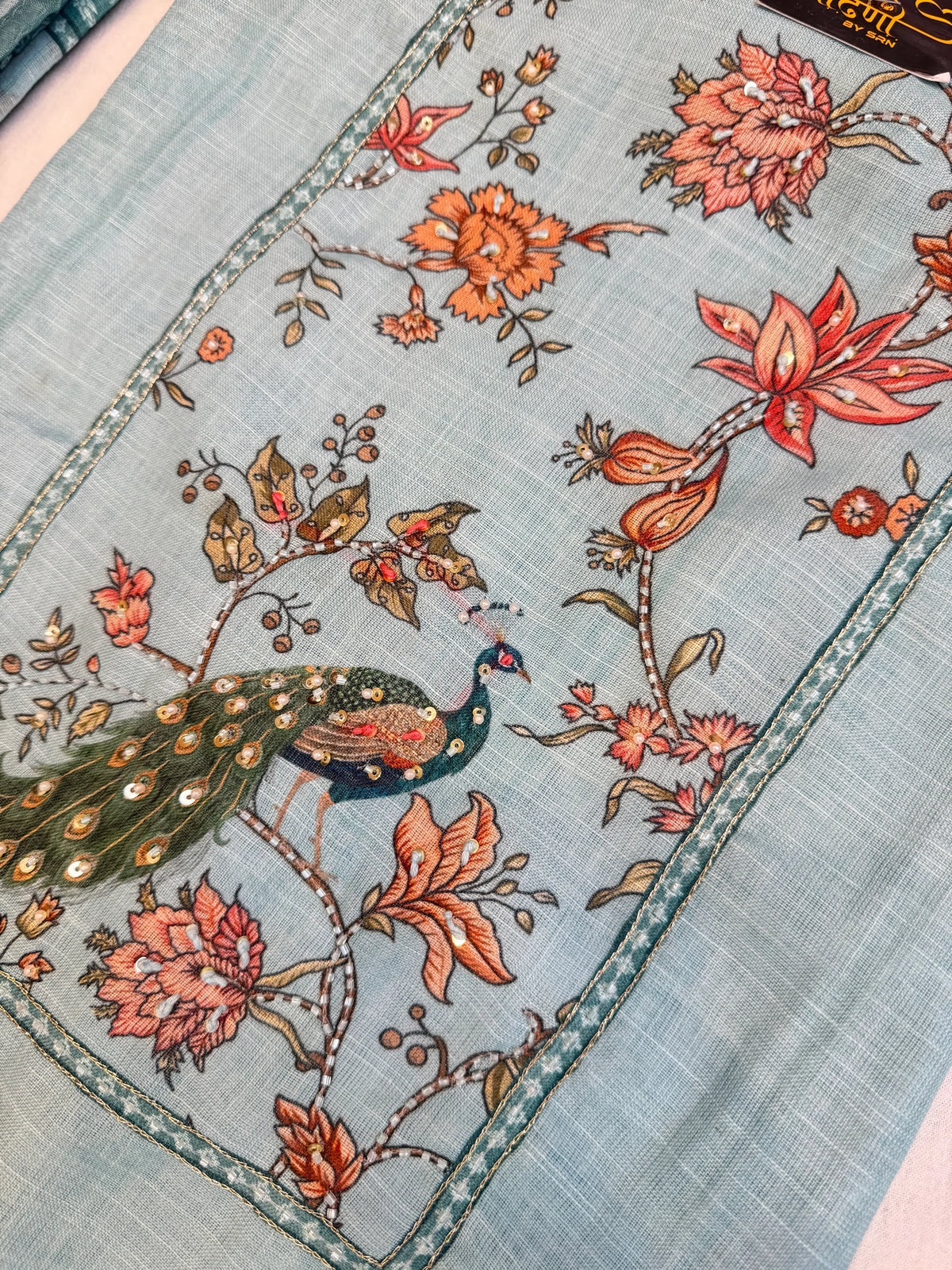 Detailed front panel image of sky blue cotton doria suit showing handworked peacock motif with sequins and zari work