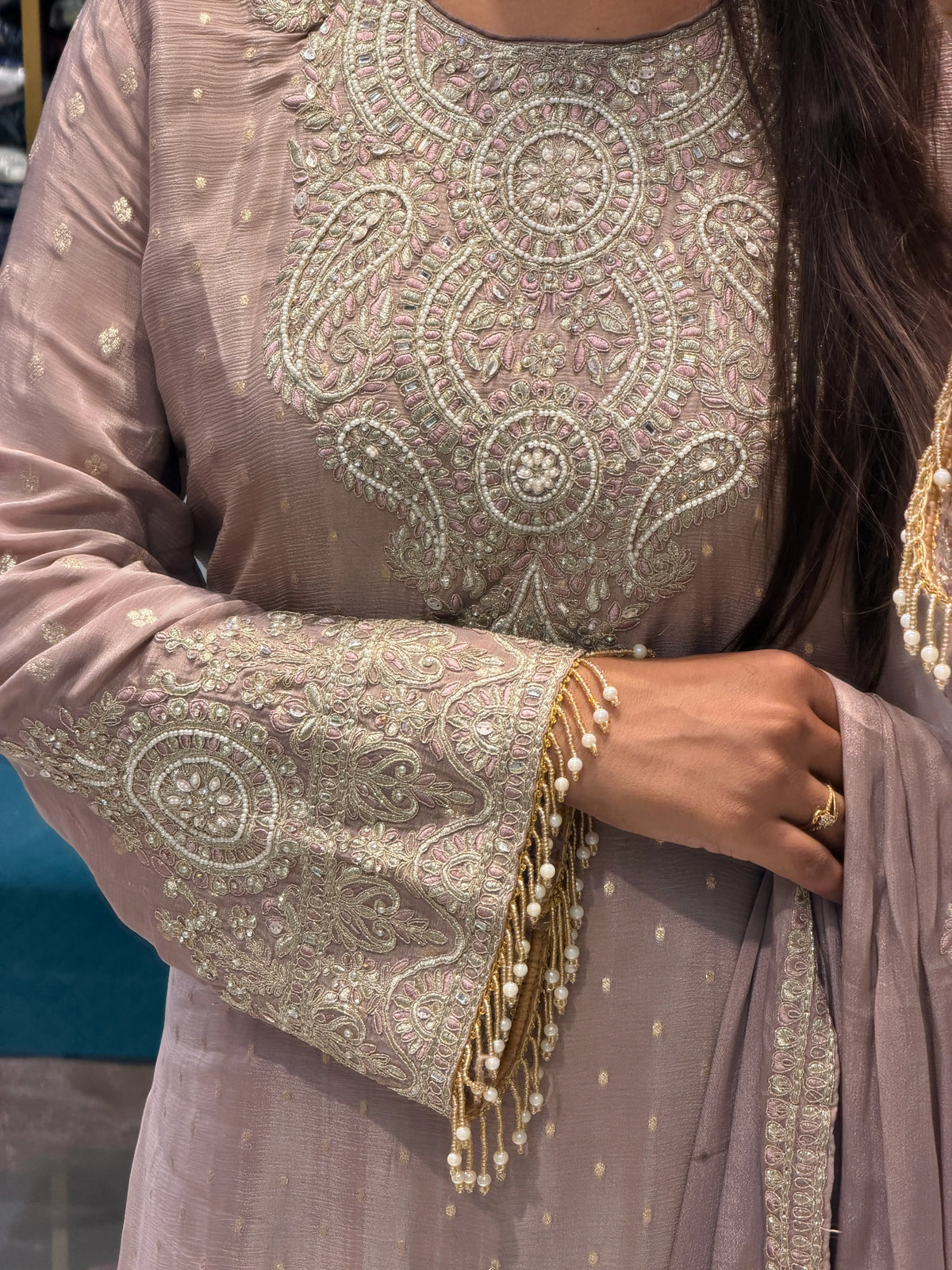 Close up view of heavy Zari embroidery, pearl handwork neckline, and sleeve cuff fringe details