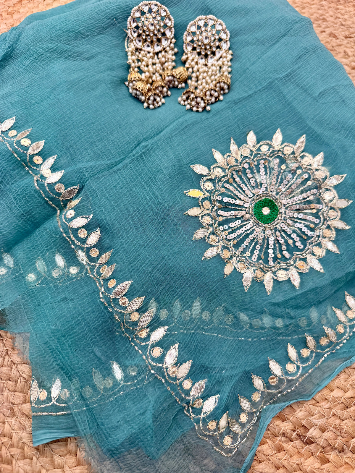 Flat layout of Turquoise Sea Green Pure Chiffon Saree displaying handcrafted sequin border and chakra motif