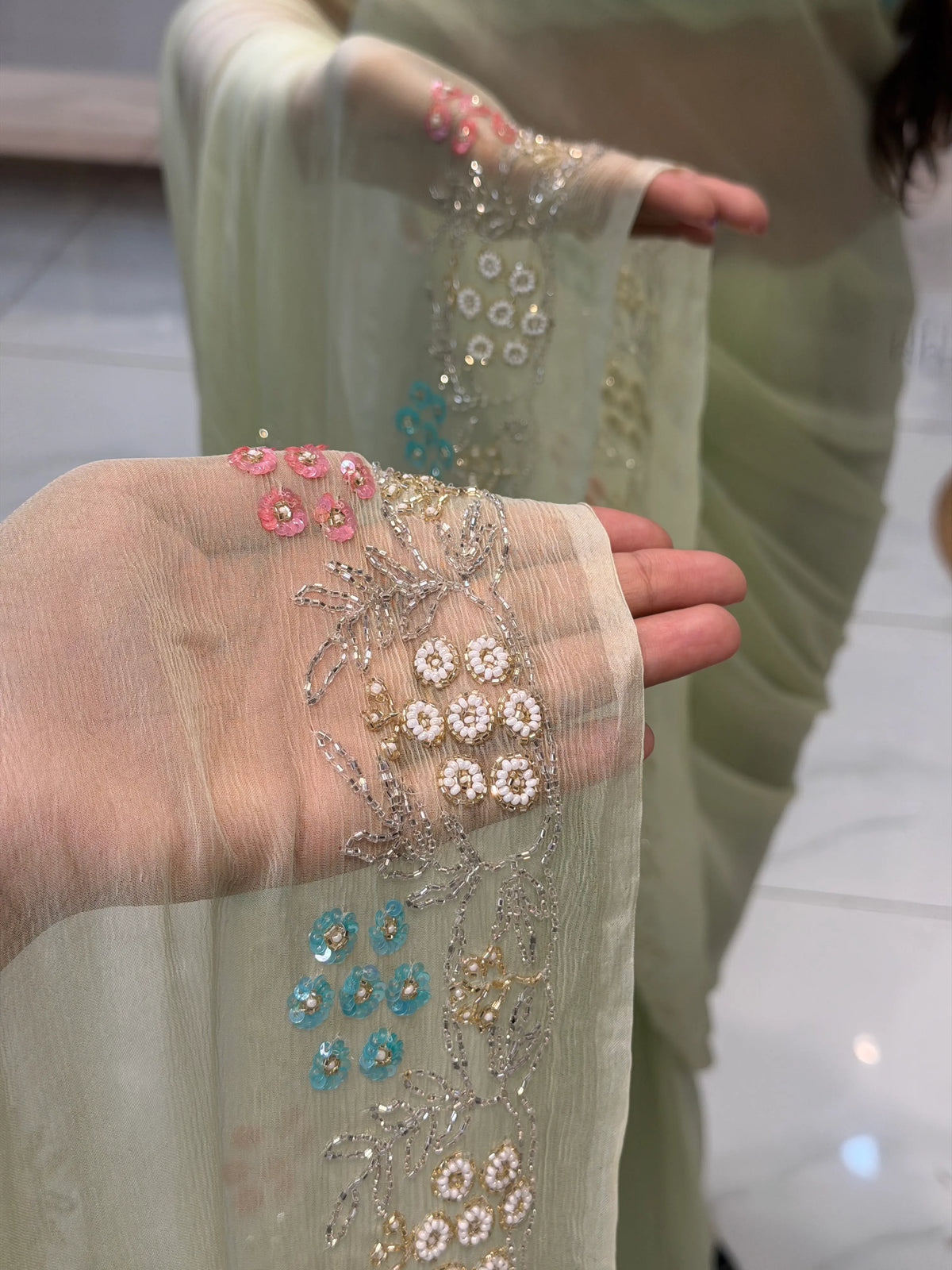 Macro close-up of pure chiffon sheer fabric showing white pearl flower clusters and pink sequin work