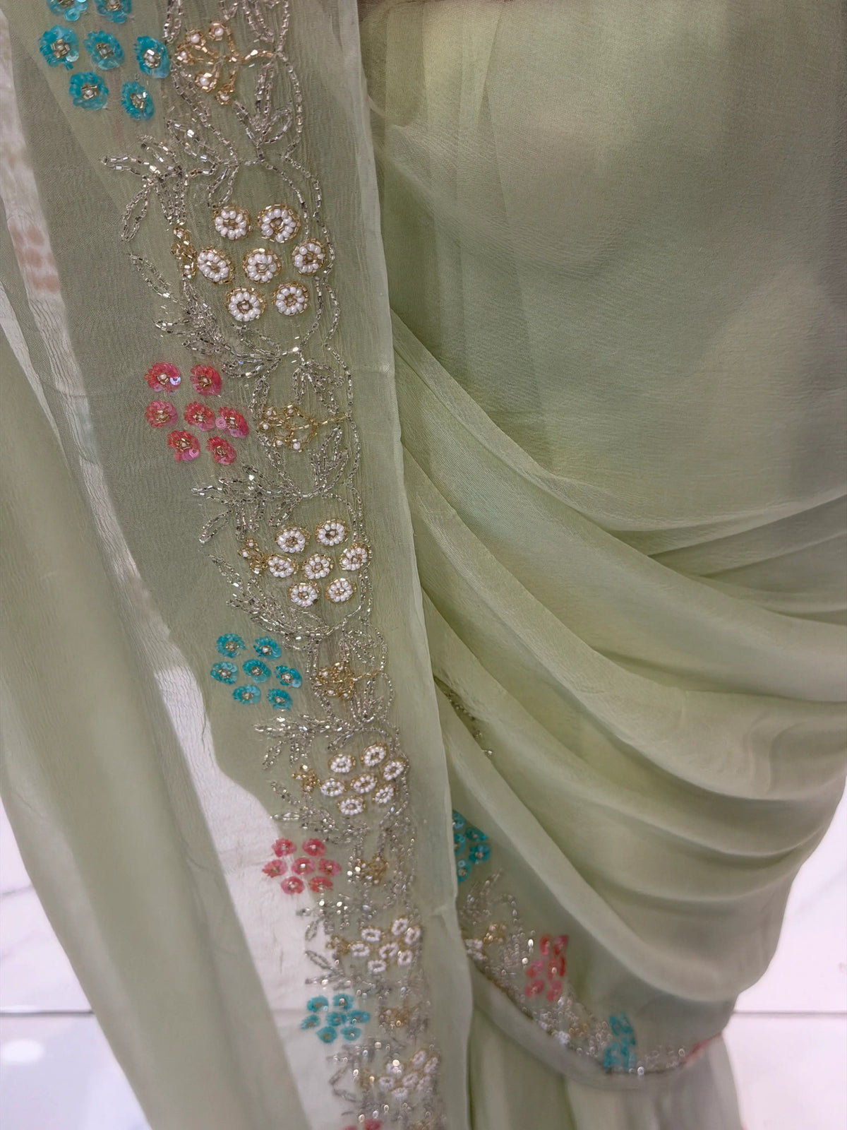 Detailed view of hand-embroidered border featuring aqua blue sequin flowers, white pearls, and silver Cut Dana