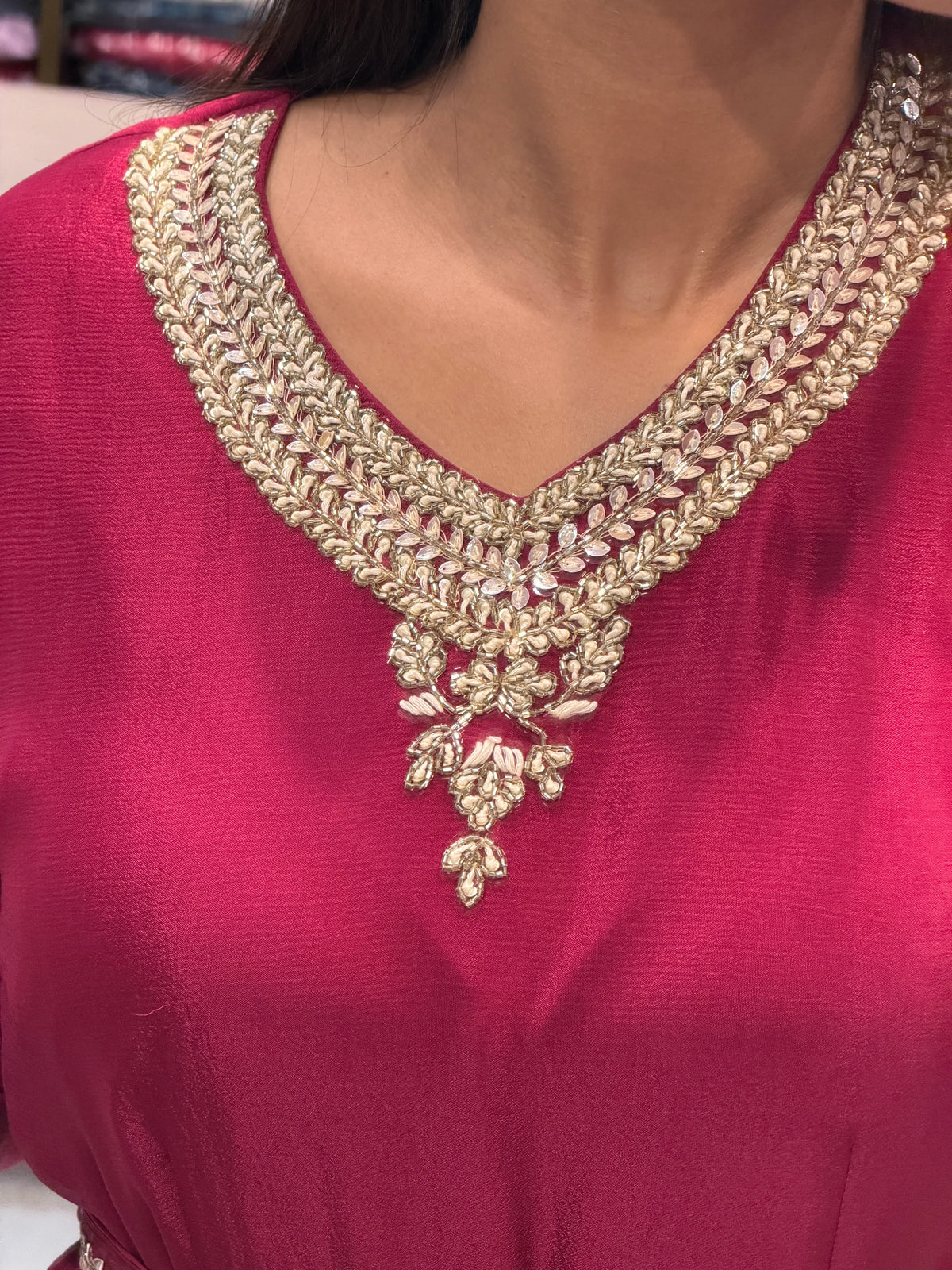 Close-up of elegant V-neckline showcasing white mulmul threadwork, silver Cut Dana, and sequin cluster border