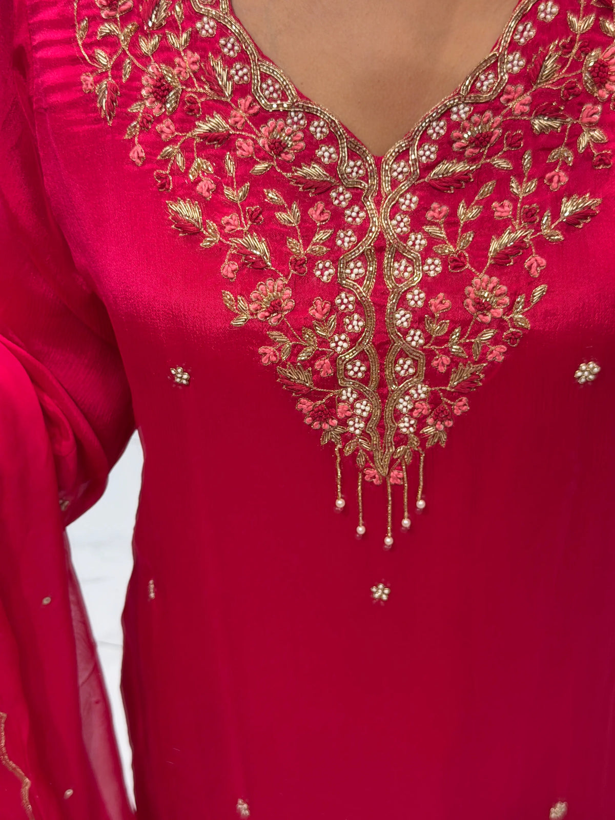 Macro close-up of V-neckline showcasing heavy Zardosi, Cut Dana, white pearls, and hanging moti drop tassels