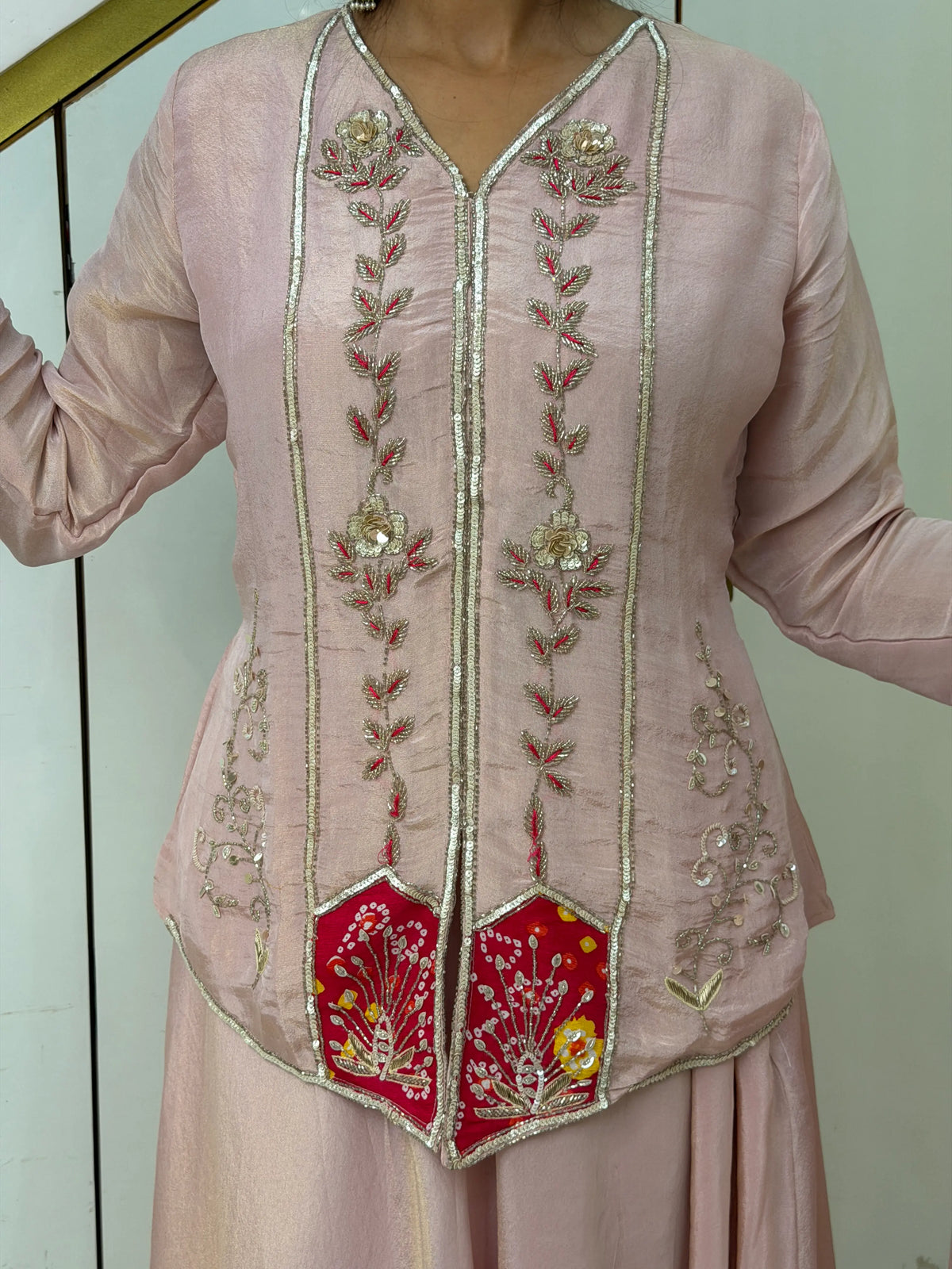 Close-up of cutdana sequins work and red patch embroidery on light pink short kurti